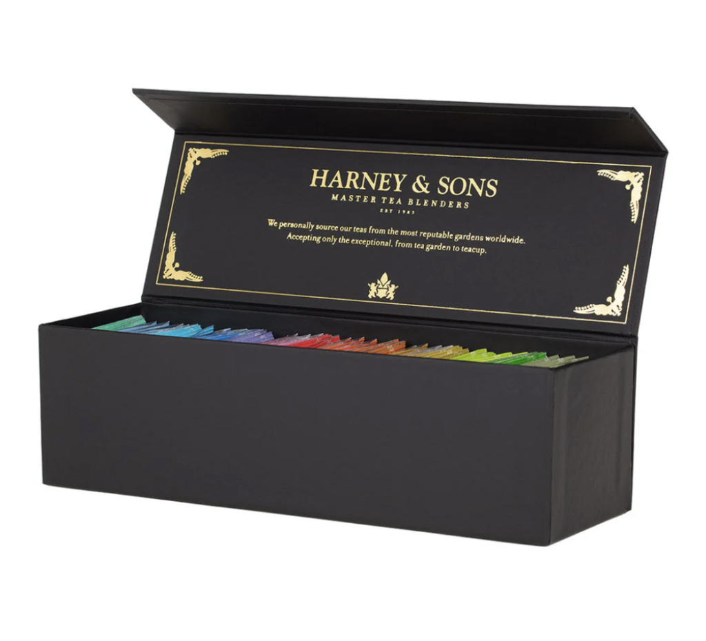 A black Harney & Sons tea collection box, with variously colored tea bags neatly arranged inside.